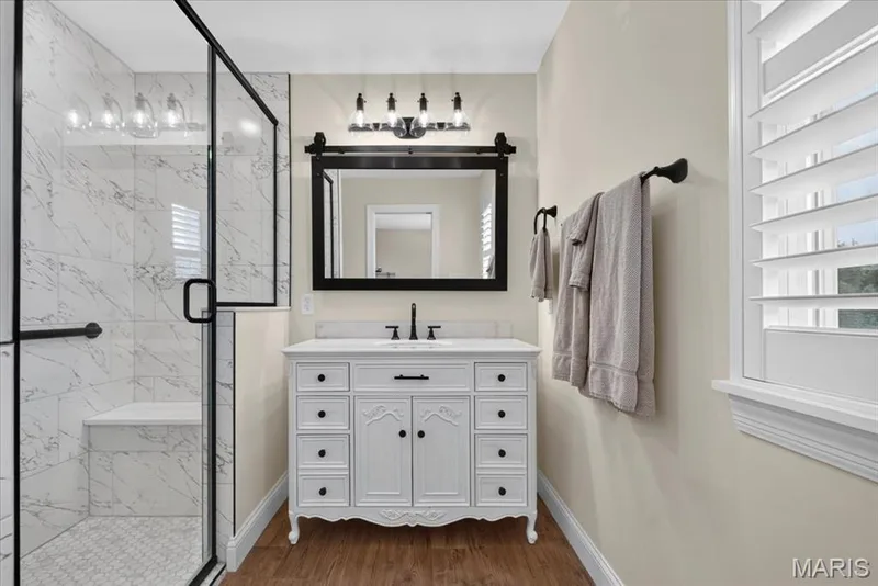 Glass-enclosed shower with a built-in bench, marble-finish tile, and a decorative mosaic floor — 3708 Broad Street, St Charles, MO 63301