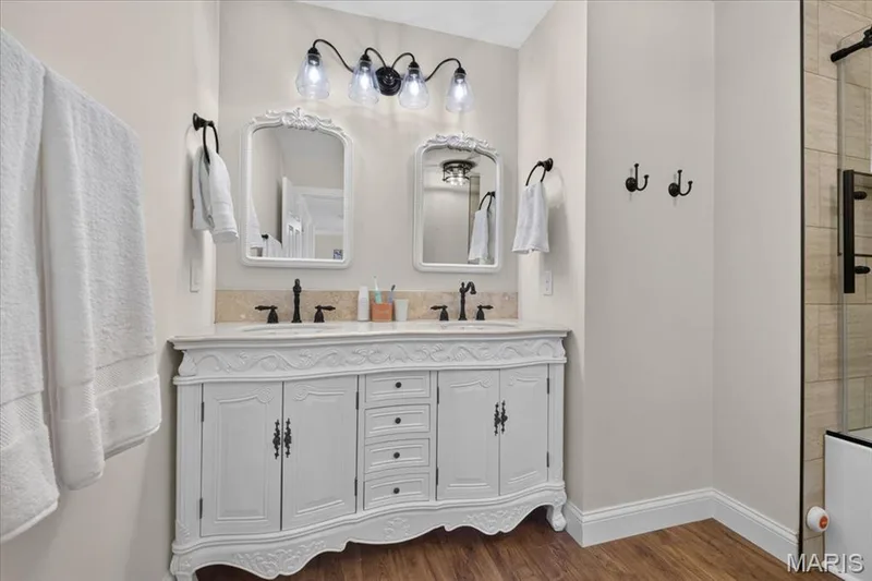 Dual vanity with decorative white cabinetry, stone countertop, and matte black fixtures — 3708 Broad Street, St Charles, MO 63301