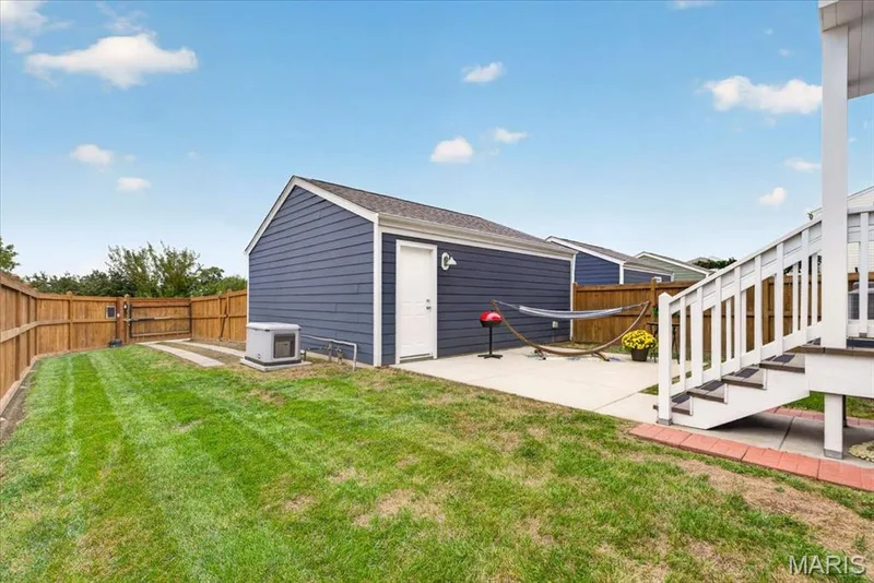Fenced backyard featuring a detached structure, concrete patio, and exterior stairs — 3708 Broad Street, St Charles, MO 63301
