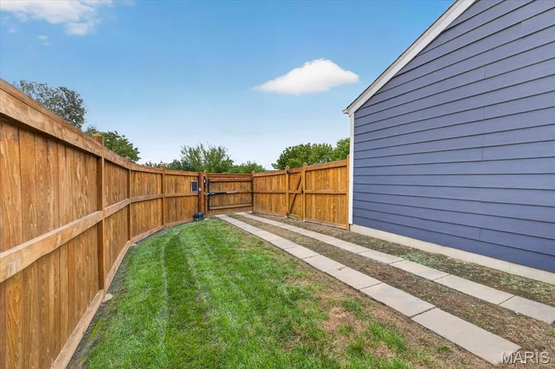 Lawn area with privacy fencing, a gate, concrete stepping stones, and horizontal siding — 3708 Broad Street, St Charles, MO 63301