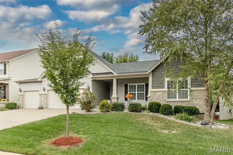 Siding exterior with stone accents, covered front entry, attached garage with two doors, and a manicured lawn — 1229 Cashmere Lane, St Peters, MO 63376