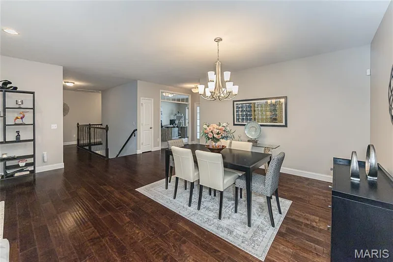 Wood-finish flooring throughout, brushed nickel chandelier, and a built-in staircase with black railing — 1229 Cashmere Lane, St Peters, MO 63376