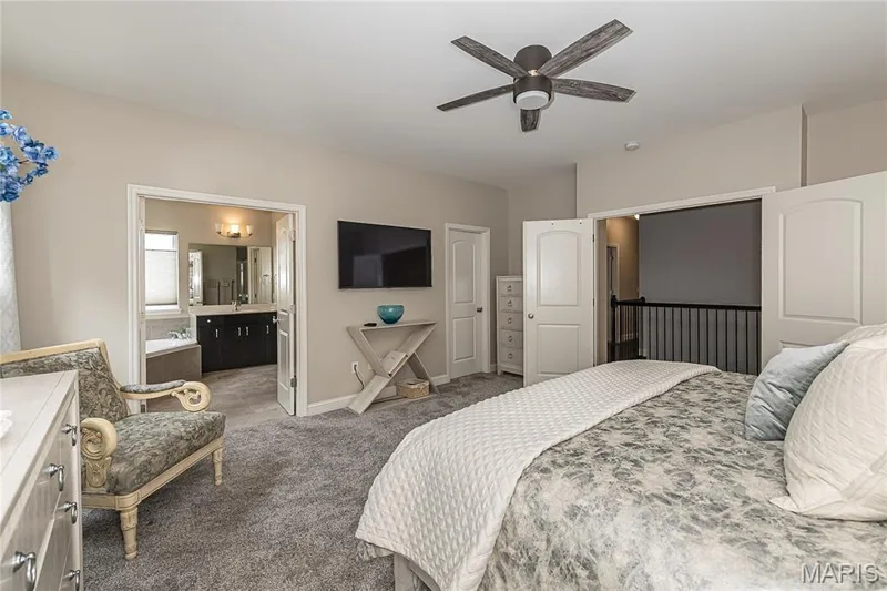 Carpeted room with a ceiling fan, direct access to a bathroom featuring a soaking tub and dual vanity, and a separate closet with bifold doors — 1229 Cashmere Lane, St Peters, MO 63376