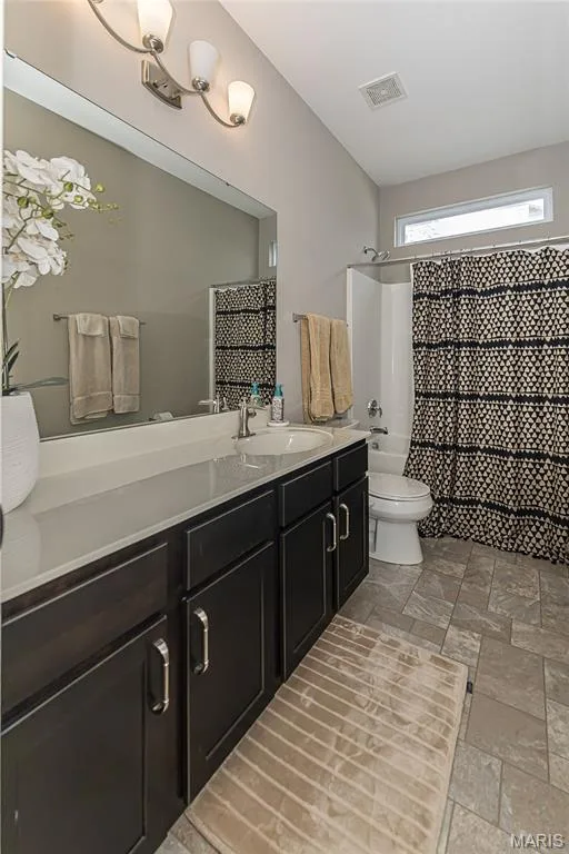 Dual vanity with dark wood-finish cabinetry, white countertop, and integrated sink — 1229 Cashmere Lane, St Peters, MO 63376