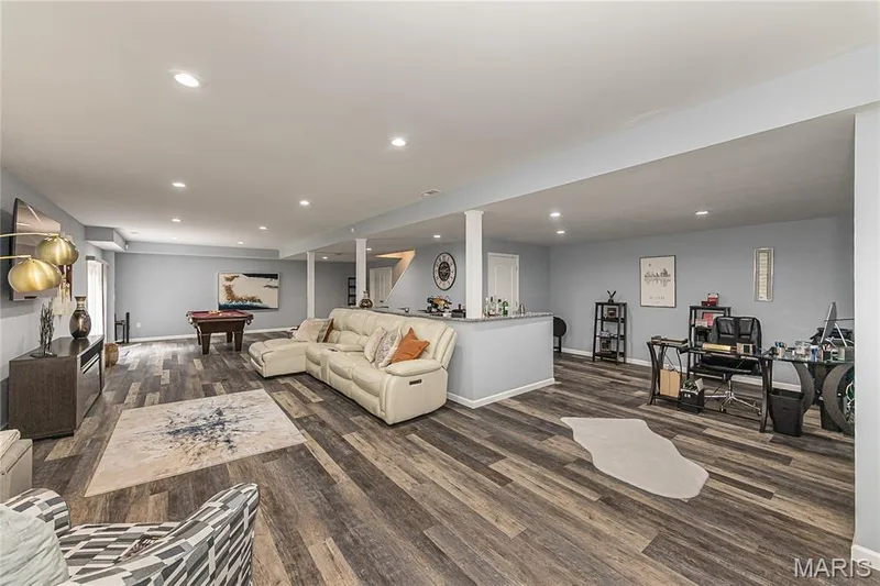 Spacious room featuring recessed lighting, wood-finish flooring, light blue wall paint, and a built-in counter with a stone-finish top — 1229 Cashmere Lane, St Peters, MO 63376