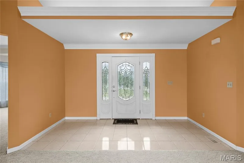 Entry foyer with tile flooring, a decorative glass front door, side panel windows, and overhead lighting — 104 Wolf Trail Court, Defiance, MO 63341