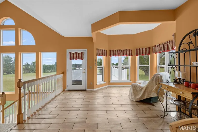 Vaulted ceiling with a half-round window, large rectangular windows, wood-finish flooring, and white spindle railing — 104 Wolf Trail Court, Defiance, MO 63341