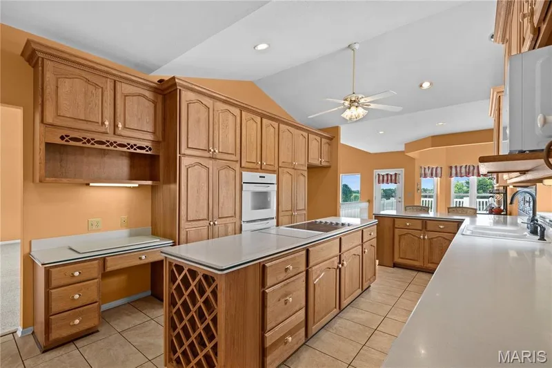 Expansive kitchen featuring wood cabinetry, white countertops, built-in appliances, recessed lighting, and a ceiling fan — 104 Wolf Trail Court, Defiance, MO 63341