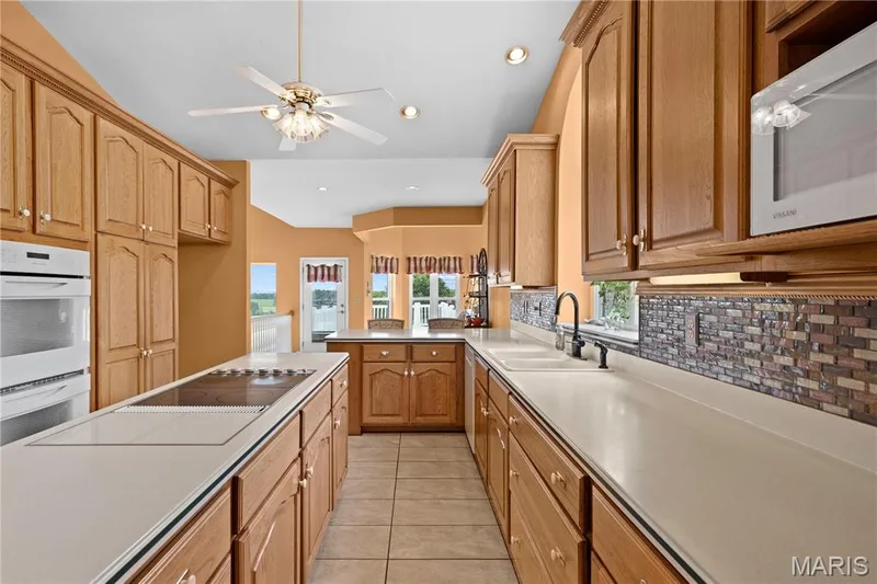 Recessed lighting, wood-finish cabinetry, tile flooring, built-in double oven, and a tiled backsplash — 104 Wolf Trail Court, Defiance, MO 63341
