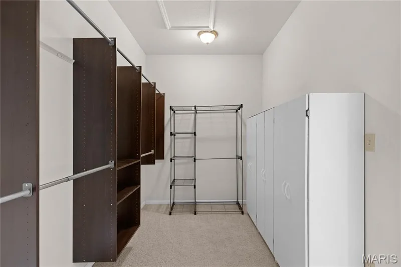 Built-in dark wood-finish shelving, metal hanging rods, and light-colored carpeting — 104 Wolf Trail Court, Defiance, MO 63341