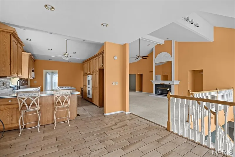 Kitchen with wood cabinetry, light-toned countertops, and tile flooring — 104 Wolf Trail Court, Defiance, MO 63341