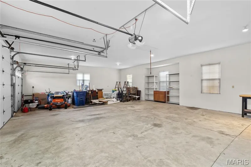 Spacious garage with two overhead doors, concrete flooring, recessed lighting, and multiple windows — 104 Wolf Trail Court, Defiance, MO 63341