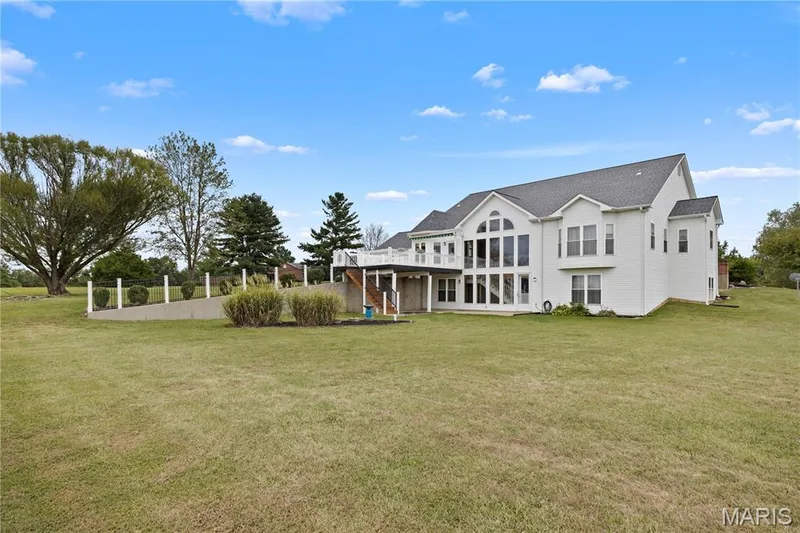 Expansive rear exterior featuring a multi-level deck, a wall of arched windows, and a large grassy area — 104 Wolf Trail Court, Defiance, MO 63341
