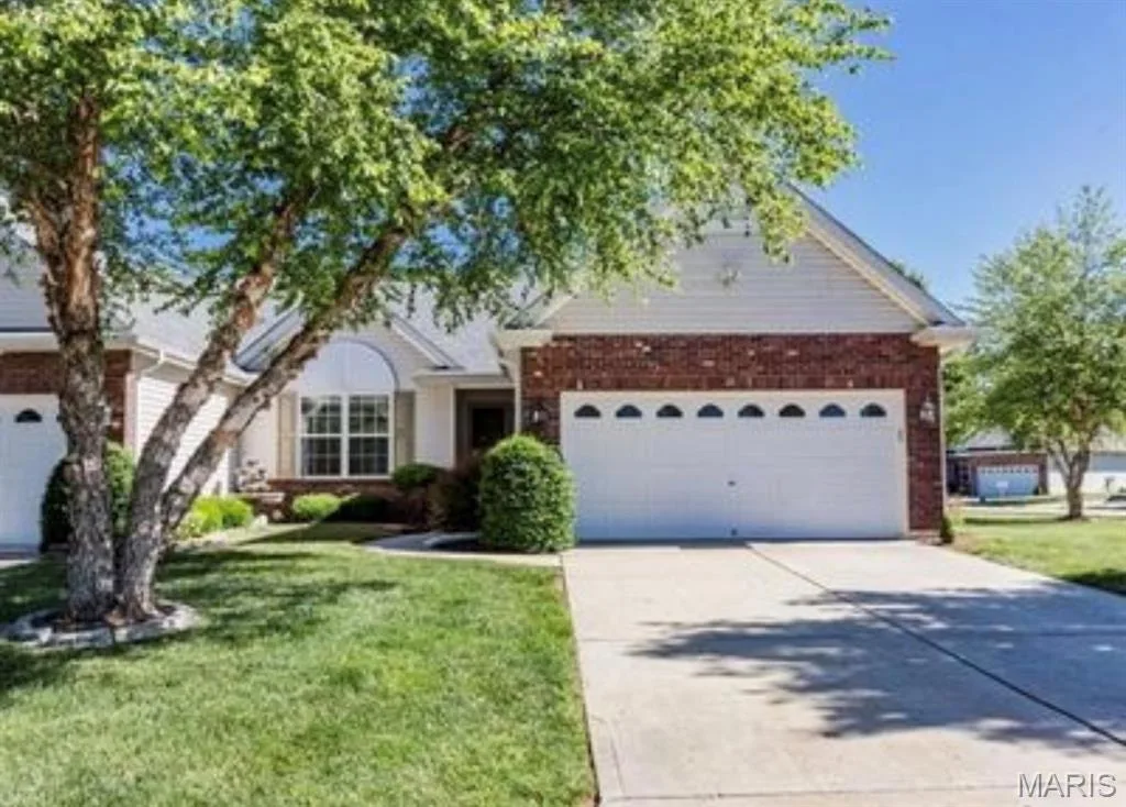 Brick and siding exterior with an arched window, attached garage, and concrete driveway — 20 Autumn Ridge Drive #83B, O'Fallon, MO 63366