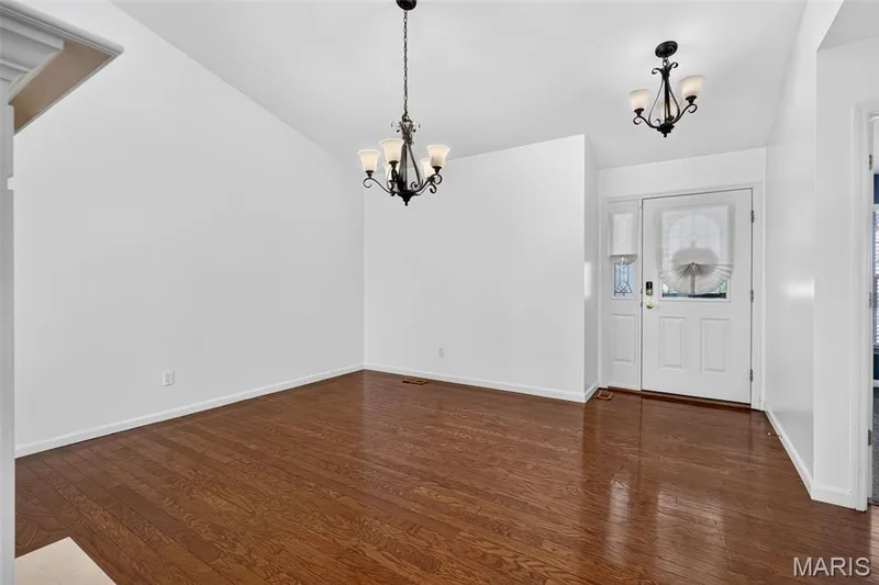Wood-finish flooring with a high-gloss finish, vaulted ceiling, white interior walls, and two decorative chandeliers — 20 Autumn Ridge Drive #83B, O'Fallon, MO 63366