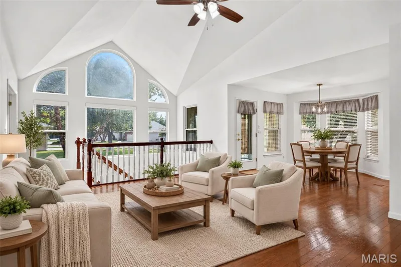 Vaulted ceiling with a ceiling fan, arched windows, and a wood-finish staircase railing with white spindles — 20 Autumn Ridge Drive #83B, O'Fallon, MO 63366