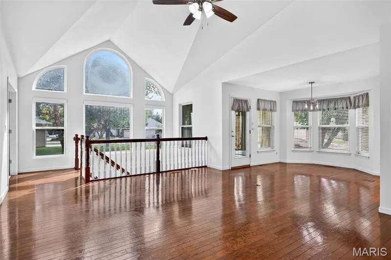 Vaulted ceilings, wood-finish flooring, a contemporary ceiling fan, and an arched window create a bright living space — 20 Autumn Ridge Drive #83B, O'Fallon, MO 63366