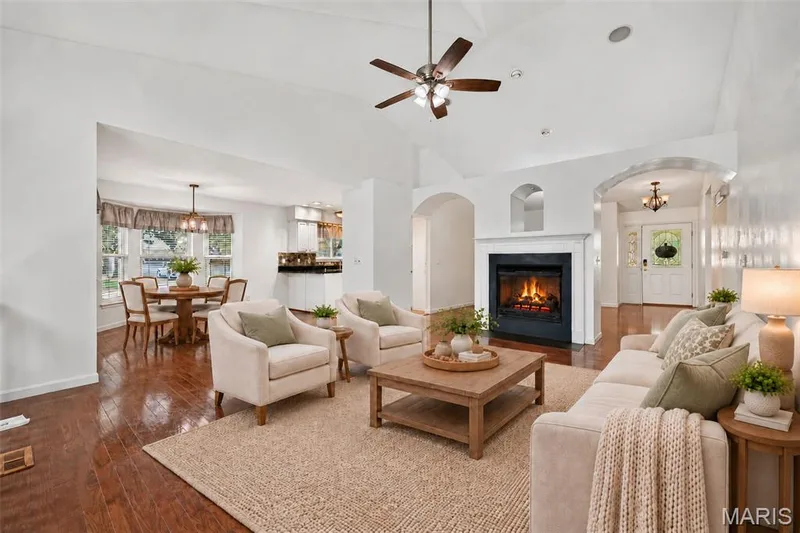 Vaulted ceilings with a ceiling fan, fireplace with a white mantel, arched doorways, and wood-finish flooring — 20 Autumn Ridge Drive #83B, O'Fallon, MO 63366