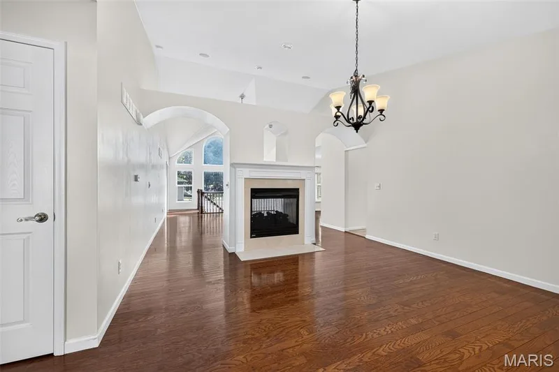Hardwood flooring, vaulted ceilings, arched doorways, fireplace with mantel, and a chandelier — 20 Autumn Ridge Drive #83B, O'Fallon, MO 63366