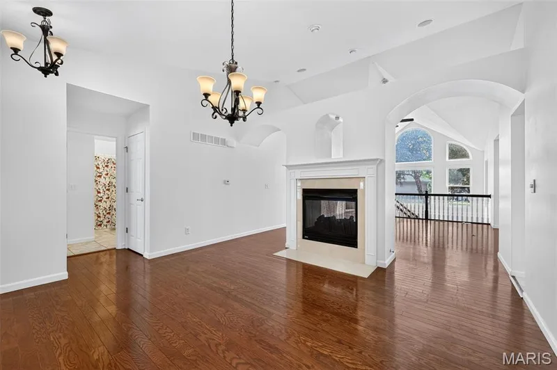 Hardwood flooring throughout, fireplace with a mantel and hearth, vaulted ceilings, arched entryways, and wrought iron balusters — 20 Autumn Ridge Drive #83B, O'Fallon, MO 63366