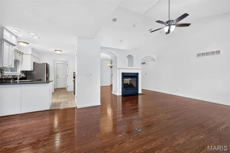 Hardwood-finish flooring, vaulted ceilings, and a fireplace with a white mantel — 20 Autumn Ridge Drive #83B, O'Fallon, MO 63366
