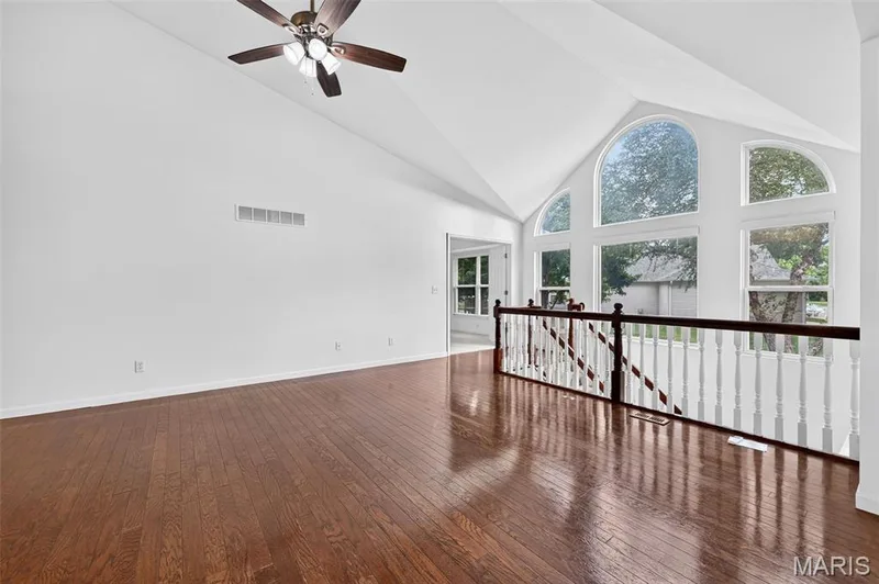 Vaulted ceiling with a ceiling fan, wood-finish flooring, and a white spindle railing — 20 Autumn Ridge Drive #83B, O'Fallon, MO 63366