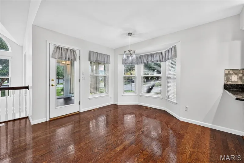 Hardwood flooring, bay window, glass-panel door, contemporary chandelier, and tile backsplash — 20 Autumn Ridge Drive #83B, O'Fallon, MO 63366