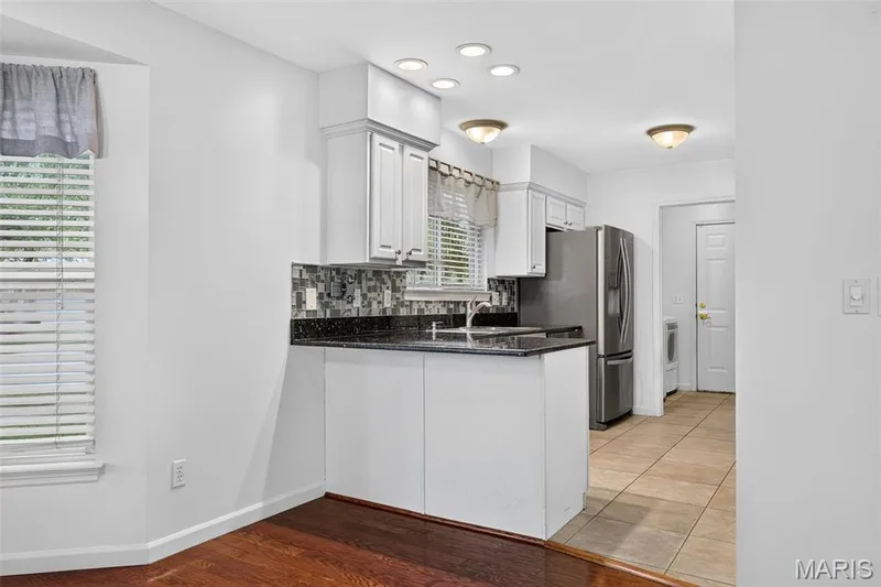 Kitchen featuring white cabinetry, dark speckled countertops, a mosaic tile backsplash, and recessed lighting — 20 Autumn Ridge Drive #83B, O'Fallon, MO 63366