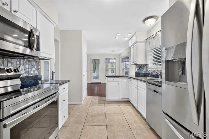 Kitchen featuring stainless steel appliances, white cabinetry, dark countertops, a tiled backsplash, and recessed lighting — 20 Autumn Ridge Drive #83B, O'Fallon, MO 63366