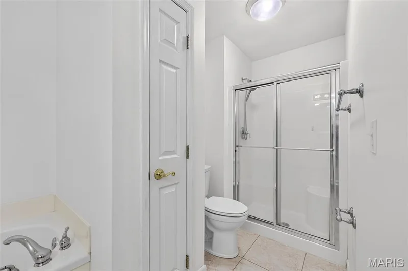 Shower enclosure with sliding glass doors, chrome fixtures, and tiled flooring — 20 Autumn Ridge Drive #83B, O'Fallon, MO 63366