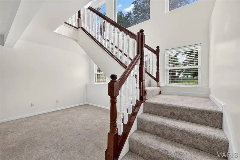 Carpeted staircase with dark wood-finish handrails and white balusters — 20 Autumn Ridge Drive #83B, O'Fallon, MO 63366