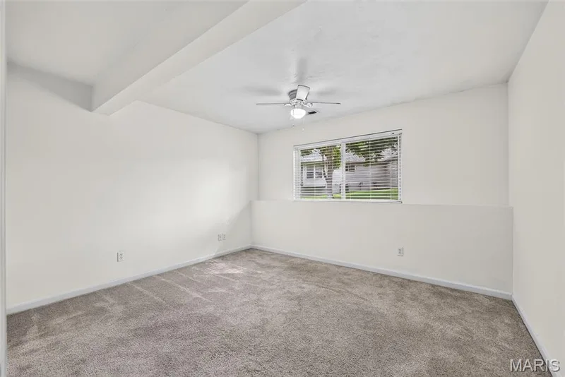 Neutral carpeted flooring, white painted walls, window with blinds, and a ceiling fan with integrated lighting — 20 Autumn Ridge Drive #83B, O'Fallon, MO 63366
