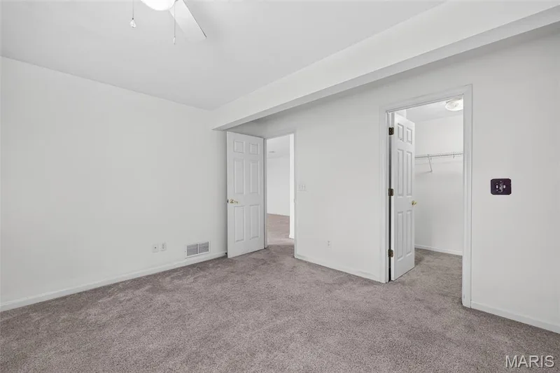 Neutral tone wall paint, gray carpet flooring, ceiling fan, white paneled doors, and a closet with wire shelving — 20 Autumn Ridge Drive #83B, O'Fallon, MO 63366