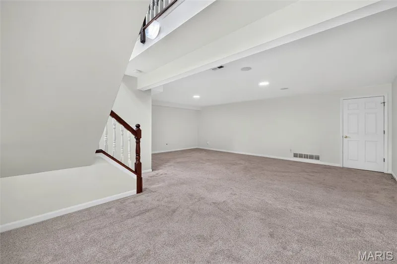 Expansive carpeted area with recessed lighting, white walls, and a white paneled door — 20 Autumn Ridge Drive #83B, O'Fallon, MO 63366