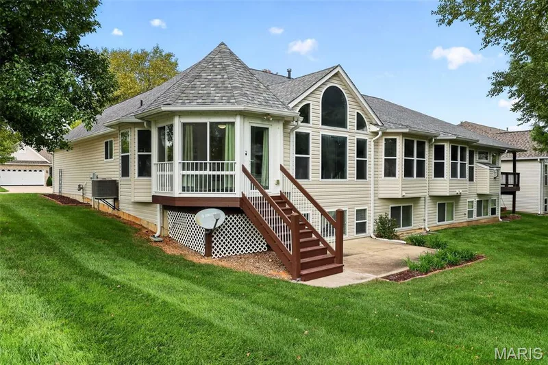 Expansive backyard with a manicured lawn, multi-level deck, and patio area — 20 Autumn Ridge Drive #83B, O'Fallon, MO 63366
