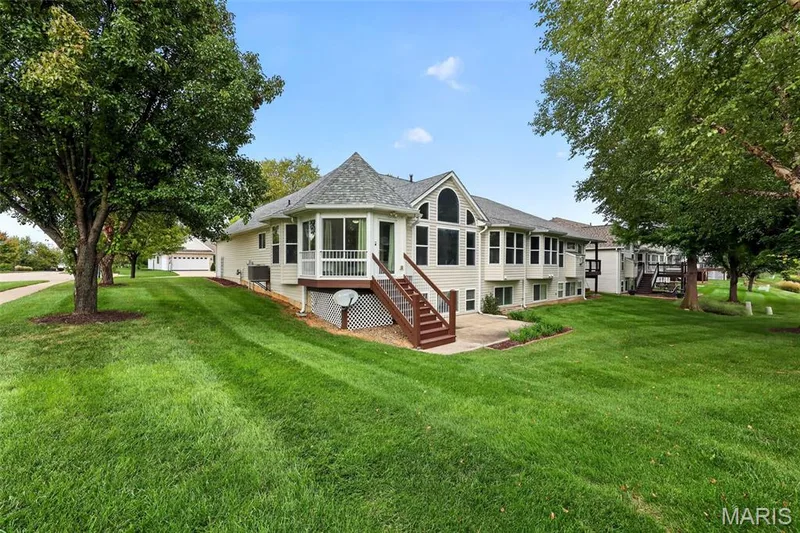 Spacious rear exterior featuring an extensive lawn, multi-level decks, and mature trees — 20 Autumn Ridge Drive #83B, O'Fallon, MO 63366