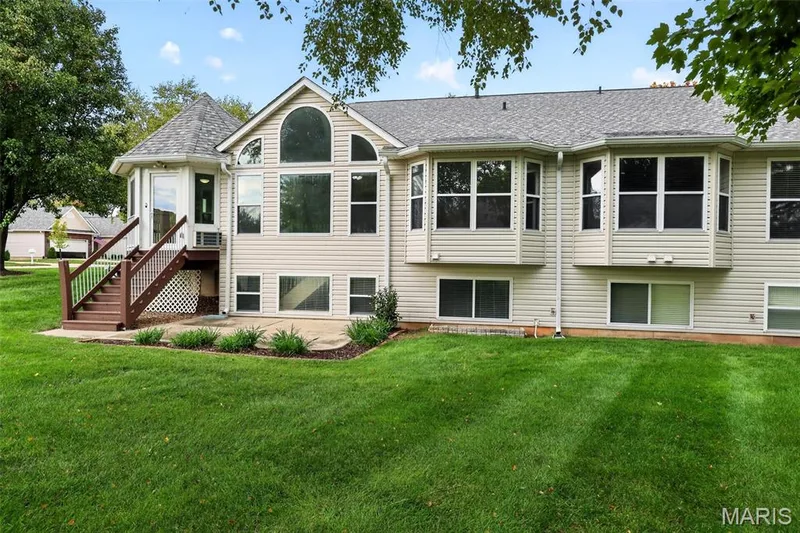 Expansive green lawn with a multi-level deck featuring wood railings — 20 Autumn Ridge Drive #83B, O'Fallon, MO 63366