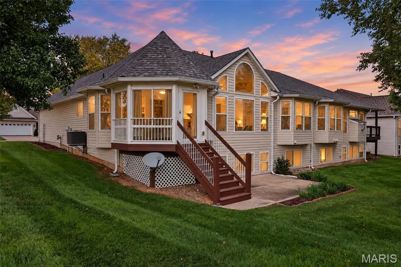 Multi-level residence featuring extensive window placements, a rounded turret sunroom, a lower-level patio, and a deck with stairs — 20 Autumn Ridge Drive #83B, O'Fallon, MO 63366