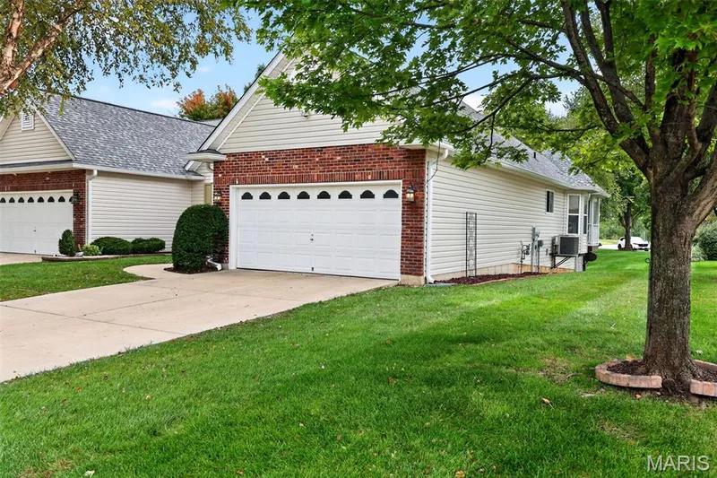 Brick and siding exterior with a two-car garage, concrete driveway, and mature landscaping — 20 Autumn Ridge Drive #83B, O'Fallon, MO 63366