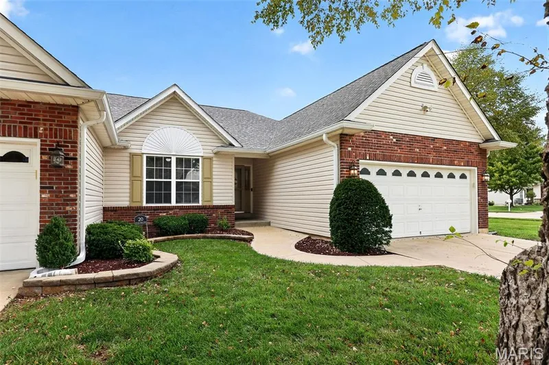 Brick and siding exterior with a two-car garage, front yard landscaping, and a concrete pathway leading to the entry — 20 Autumn Ridge Drive #83B, O'Fallon, MO 63366
