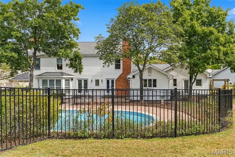 Rear exterior with white siding, fenced pool, and brick chimney — 2785 Sun Meadow Drive, Wildwood, MO 63005