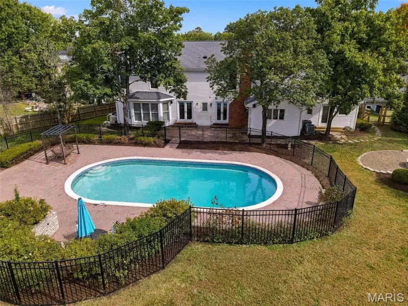 Oval swimming pool surrounded by a paver patio and metal fencing — 2785 Sun Meadow Drive, Wildwood, MO 63005