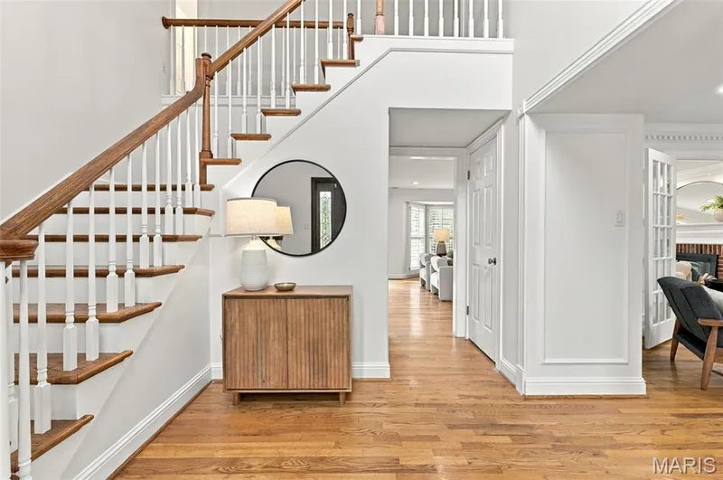 Hardwood flooring, white painted walls, wood staircase with white balusters, white trim work, and French doors — 2785 Sun Meadow Drive, Wildwood, MO 63005