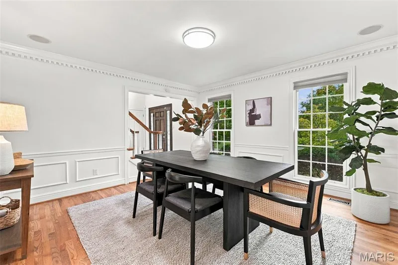 Warm wood-finish flooring with white paneled wainscoting and crown molding — 2785 Sun Meadow Drive, Wildwood, MO 63005
