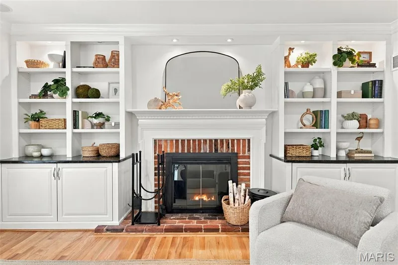 Built-in shelving with integrated lighting, brick fireplace with mantel, dark countertops, and wood-finish flooring — 2785 Sun Meadow Drive, Wildwood, MO 63005