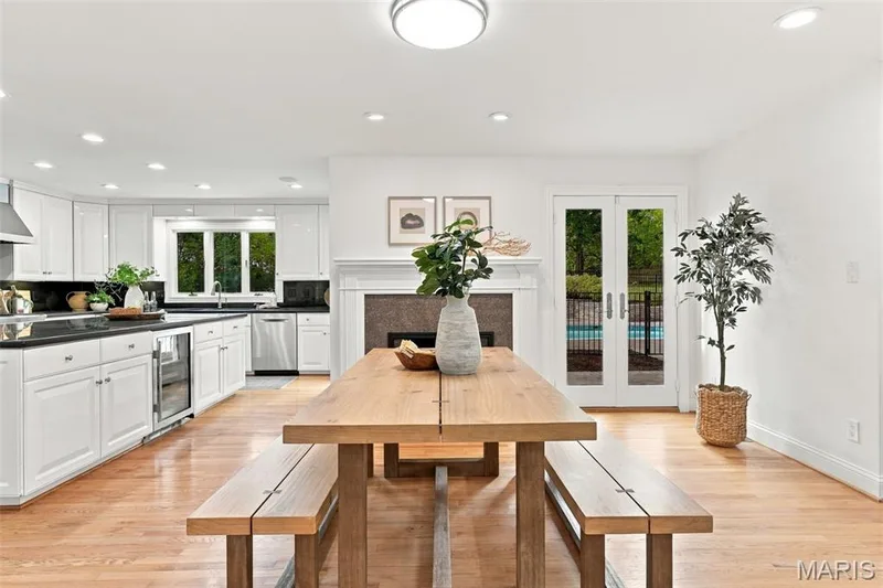 Open-concept kitchen with white cabinetry, black countertops, stainless steel appliances, and wood-finish flooring — 2785 Sun Meadow Drive, Wildwood, MO 63005
