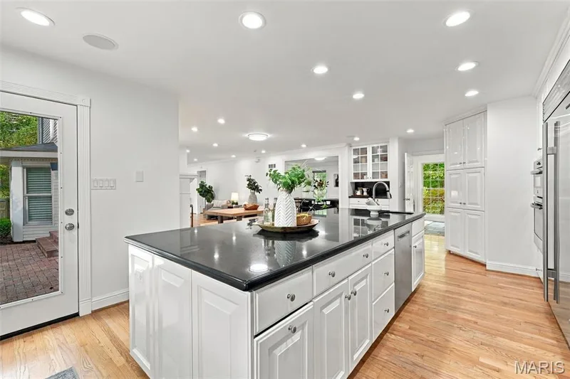 Kitchen featuring a spacious island with a dark countertop, white shaker-style cabinetry, and wood-finish flooring — 2785 Sun Meadow Drive, Wildwood, MO 63005