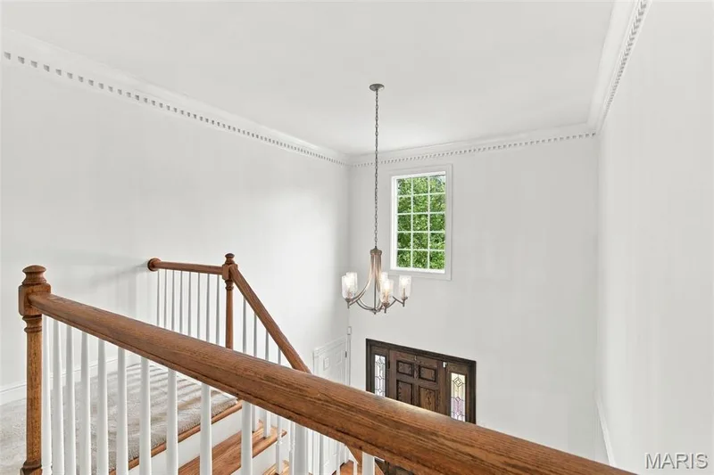High ceilings with decorative crown molding, a wood staircase with white balusters, and a grid-pane window — 2785 Sun Meadow Drive, Wildwood, MO 63005