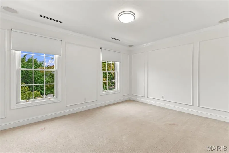 Dual windows with roller shades, recessed ceiling speakers, decorative wall molding, flush-mount ceiling fixture, and neutral carpeting — 2785 Sun Meadow Drive, Wildwood, MO 63005