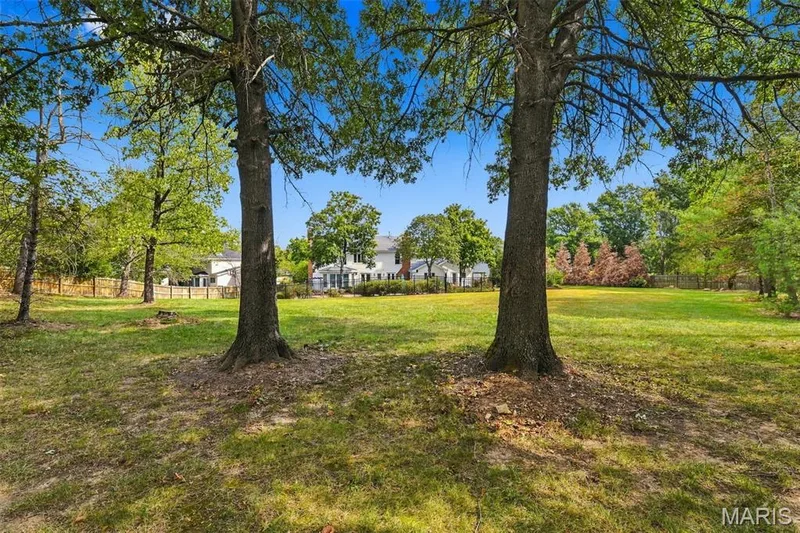 Expansive green lawn with mature trees and a white multi-story residence in the background — 2785 Sun Meadow Drive, Wildwood, MO 63005